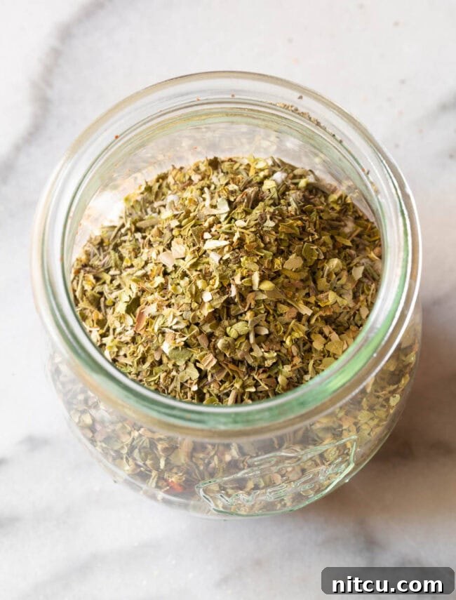 Overhead view of homemade blackened seasoning in a clear glass jar, ready for use.