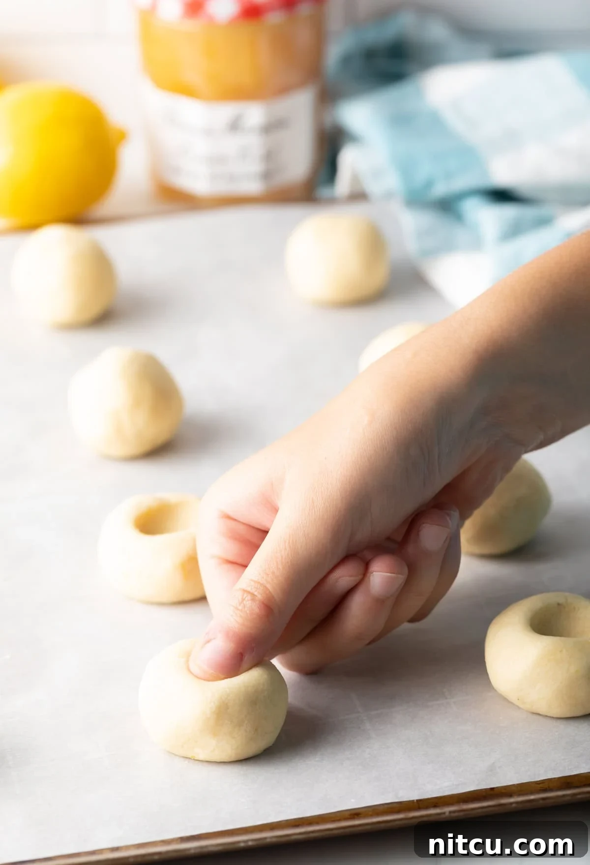 Sunshine Lemon Drop Cookies 4 Sheet pan with the lemon thumbprint cookies dough balls and using a thumb to press the indents for the lemon custard