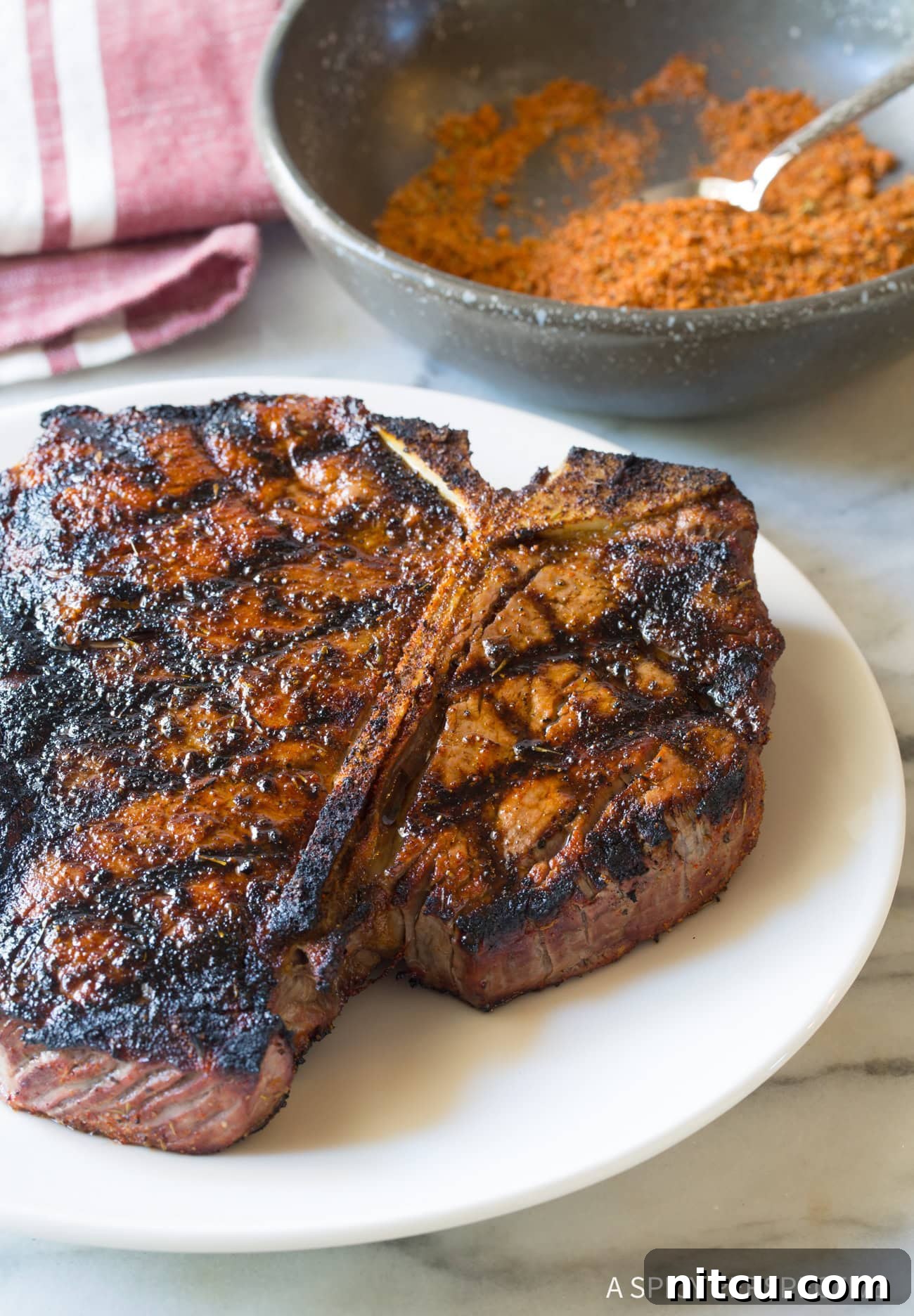 Perfectly Grilled Beef with Homemade Seasoning A perfectly grilled steak on a white plate, with a small bowl of the homemade steak seasoning in the background, ready to be served.