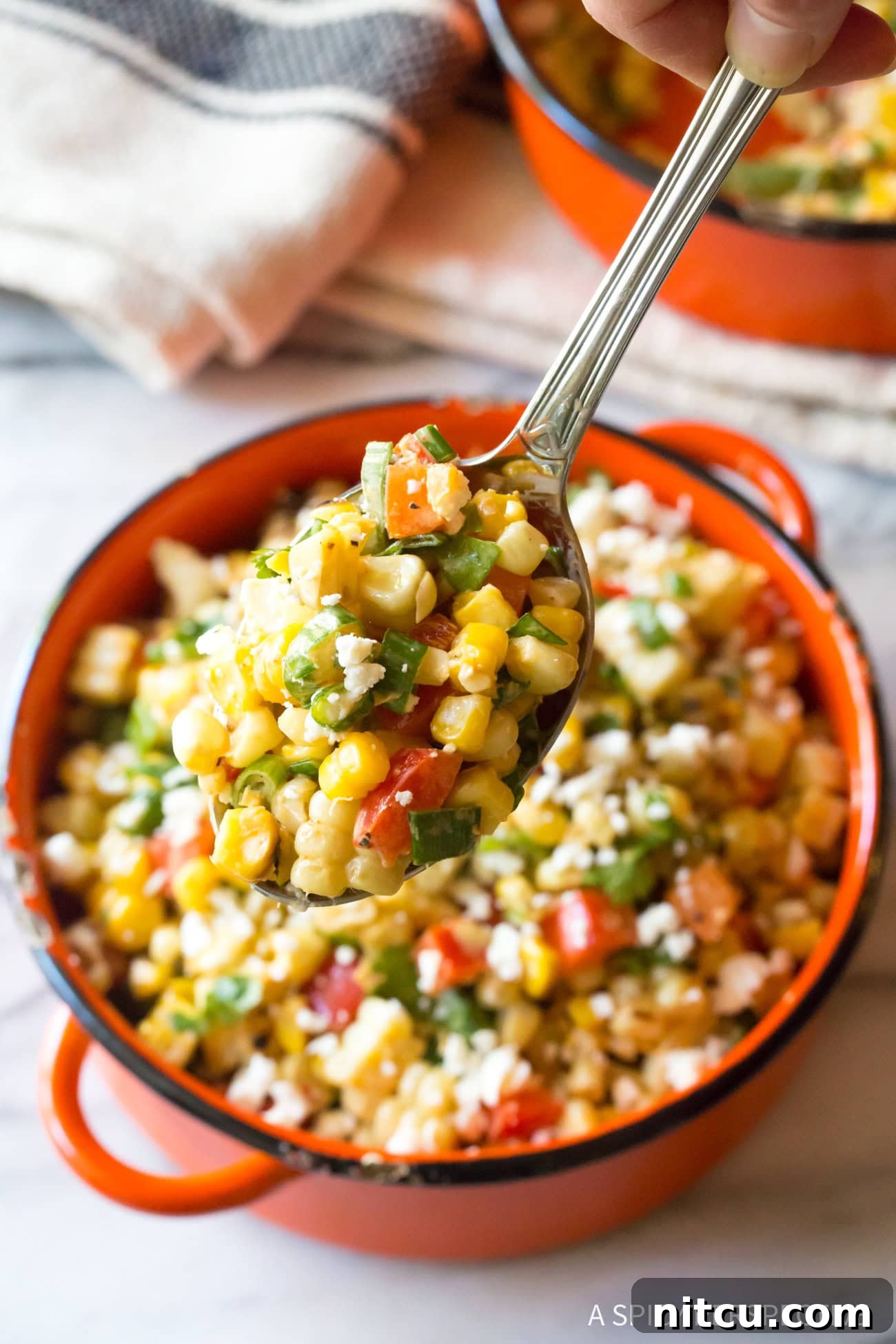 Charred Mexican Elote 11 Closeup of a spoon lifting a perfect scoop of vibrant Mexican Street Corn Salad from the bowl, ready to be enjoyed.