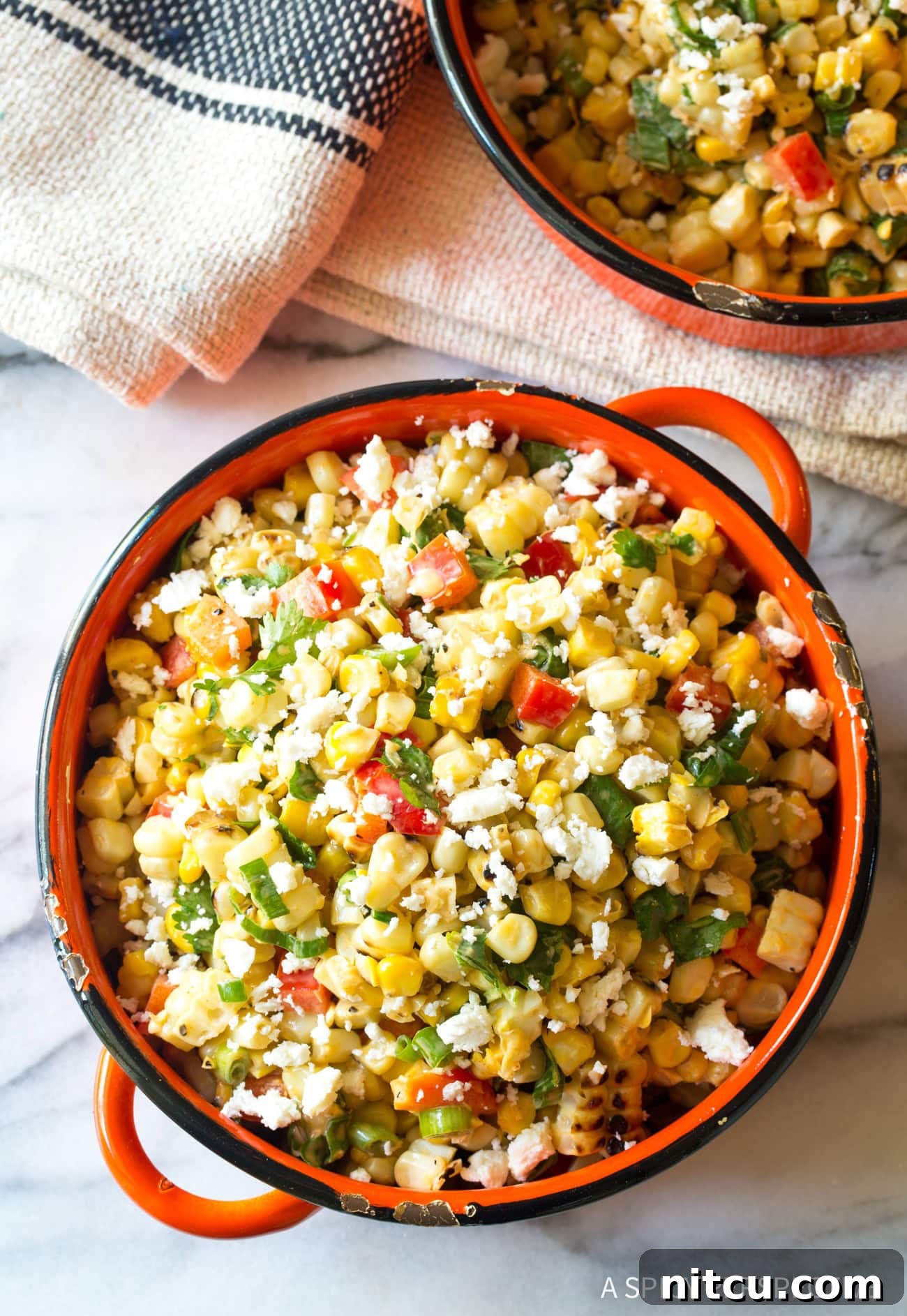 Charred Mexican Elote 4 Overhead view of a beautifully prepared grilled Mexican street corn salad in a vibrant bowl, garnished with fresh herbs and cheese.