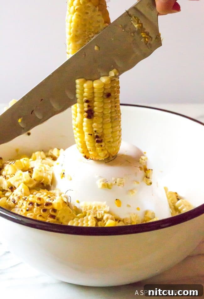 Charred Mexican Elote 7 Closeup of a knife expertly removing corn kernels from the cob into a bowl, demonstrating the technique for preparing esquites.