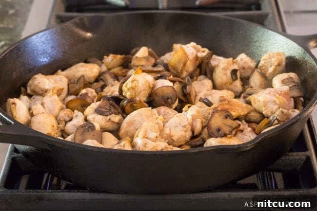 Lighter Chicken A La King 8 Cooked mushrooms and chicken browning in a skillet.