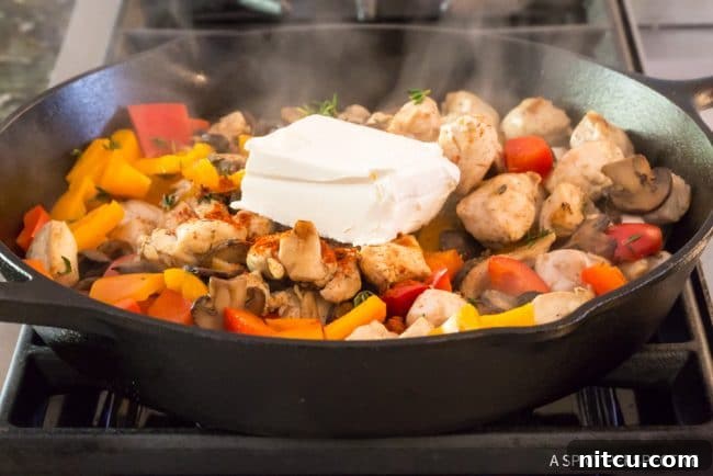 Lighter Chicken A La King 10 Chicken and vegetables topped with dollops of cream cheese in a skillet, ready to melt into sauce.