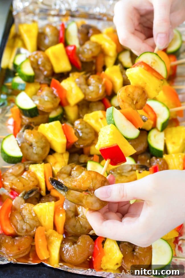 Sweet and Savory Glazed Teriyaki Shrimp 9 Closeup of a hand skillfully skewering shrimp and colorful vegetables onto wooden skewers.