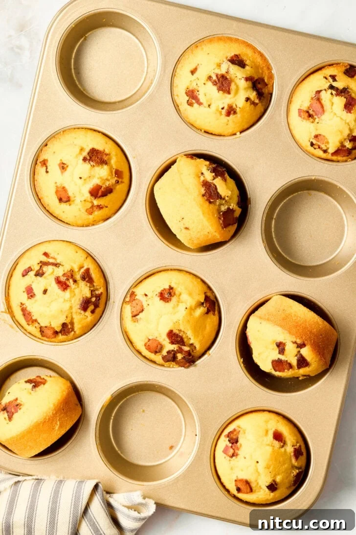 Golden Corn Muffins with Crispy Bacon 2 Warm cornbread muffins in a pan, garnished with bacon and maple syrup