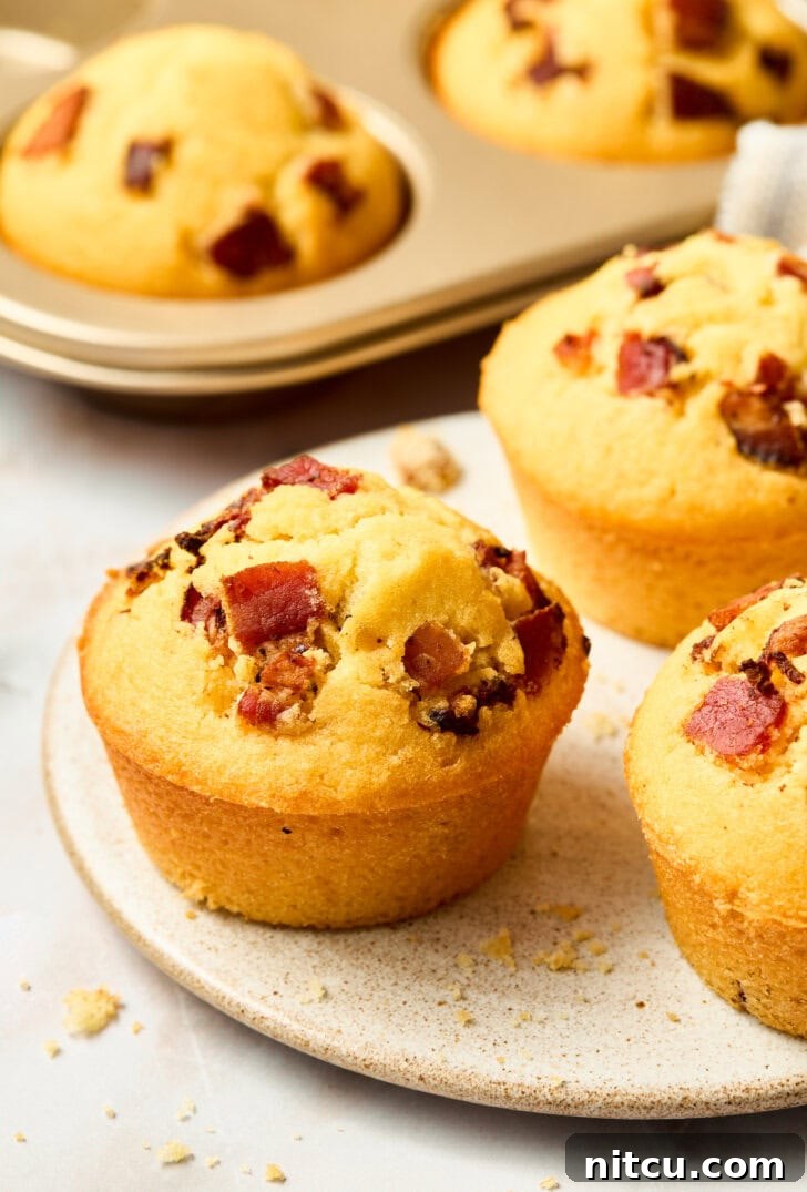 Golden Corn Muffins with Crispy Bacon 3 Plated warm cornbread muffins with maple syrup and bacon on top