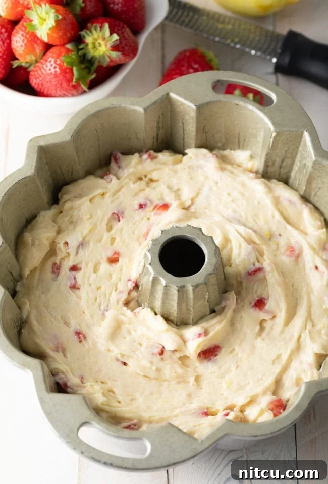Strawberry Bliss Bundt 9 Strawberry cake batter evenly poured into a silver bundt pan, ready for baking.