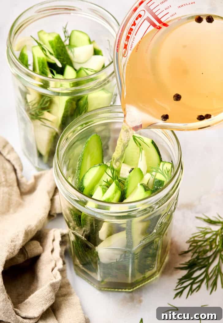 Fast & Fresh Pickles 7 Refrigerator Pickles in jar up close - warm brine being poured into jars over packed cucumbers and spices