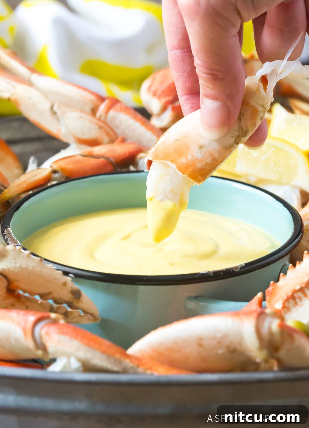 Spicy-Mustard-Sauce A hand gently dipping a piece of crab meat into a small bowl of the creamy, spicy mustard sauce, capturing the perfect bite.