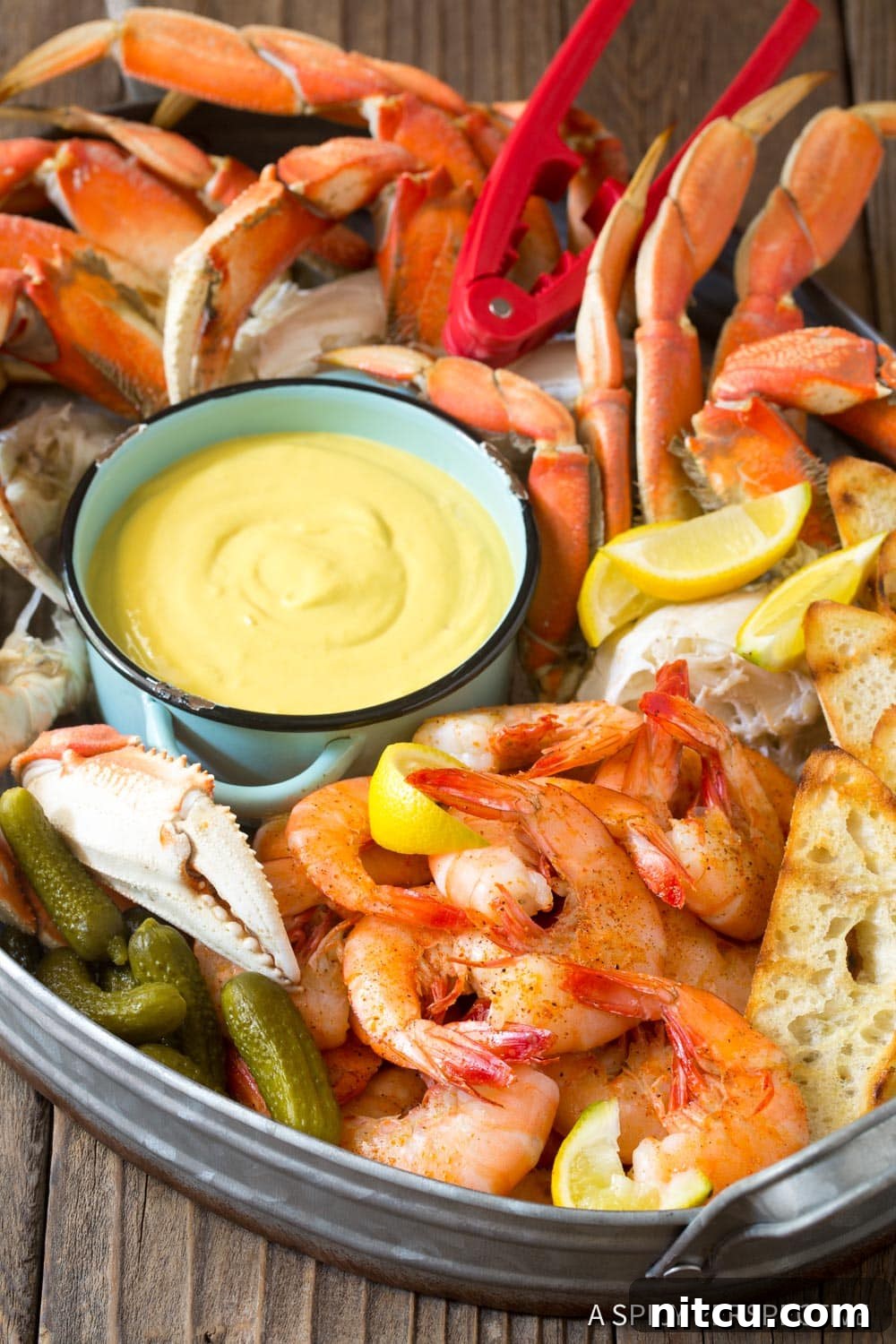Best-Spicy-Mustard-Seafood-Sauce A vibrant seafood platter featuring cooked shrimp, crab legs, and lemon wedges, with a small bowl of spicy mustard seafood sauce at the center.