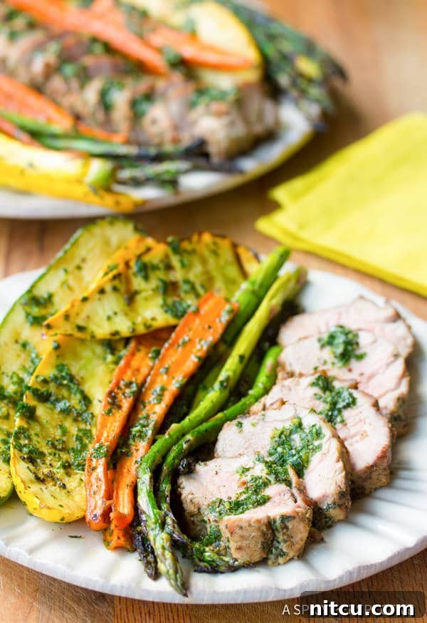 Flame-Kissed Pork Tenderloin with Bright Chimichurri and Rustic Roast Vegetables 8 A beautifully plated single serving of grilled pork tenderloin with a side of roasted vegetables and a generous dollop of chimichurri sauce, on a rustic plate.