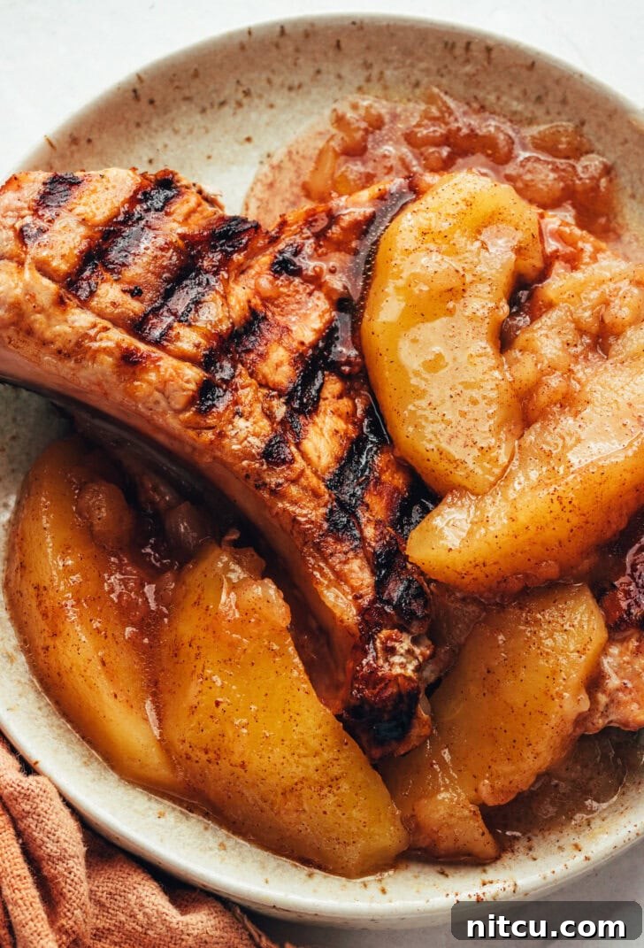 cinnamon-apples cinnamon apples on top of a grilled pork chop on a white plate.