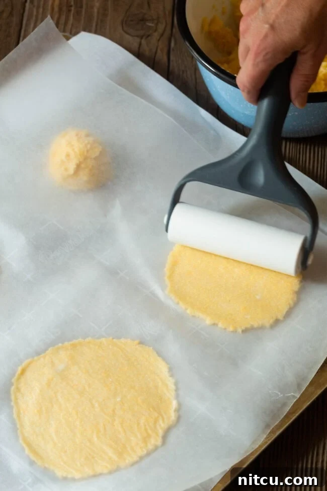 ketogenic Tortilla dough portions being rolled out on a parchment-lined baking sheet.