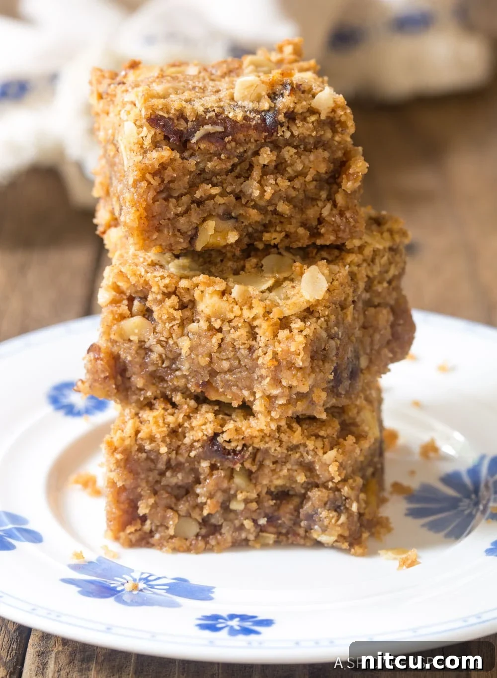 Wholesome Eggless Oat Bars 2 Soft, sweet oat breakfast bars stacked on a rustic wooden surface.