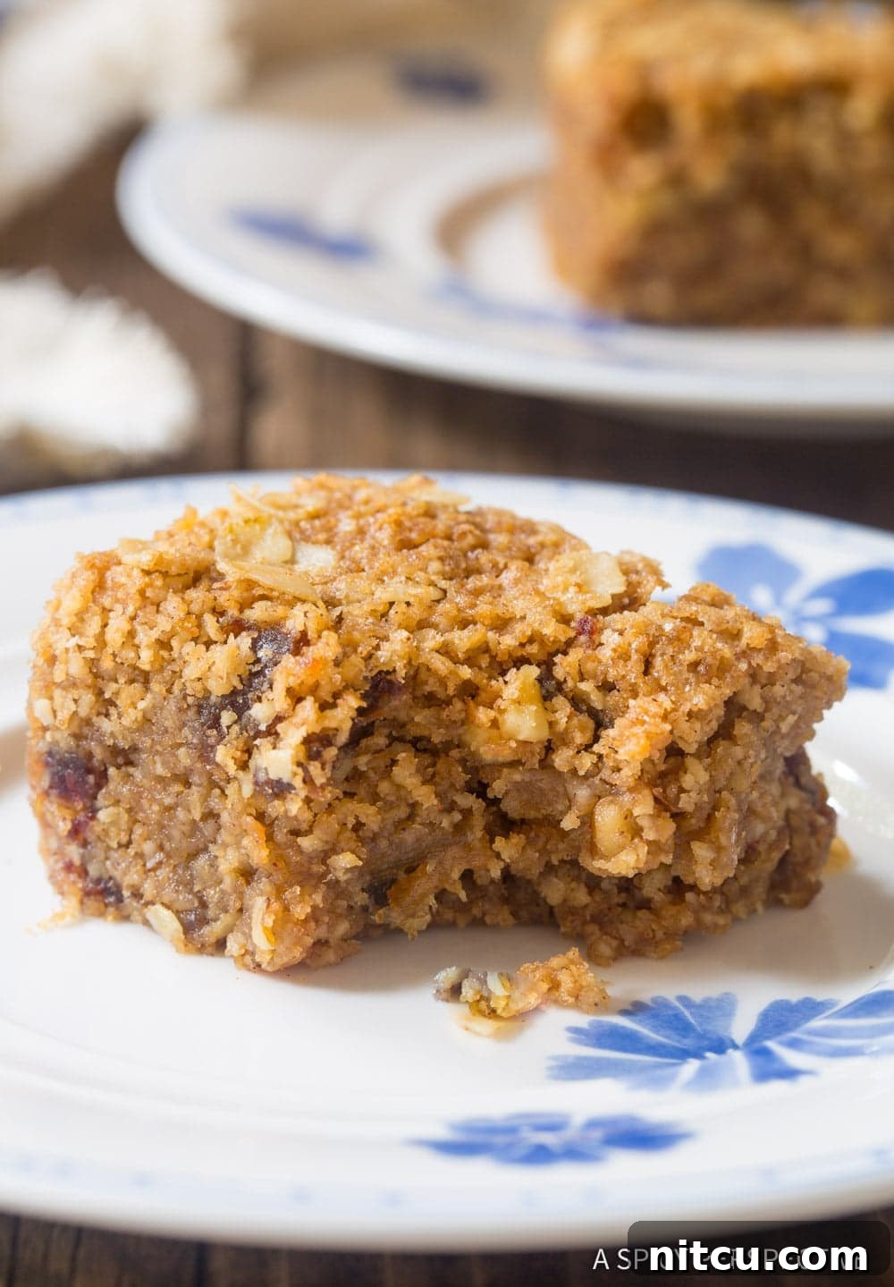 Wholesome Eggless Oat Bars 5 A close-up shot of a healthy egg-free oatmeal bar on a plate with a bite taken out, showing the oat, date, and nut texture.