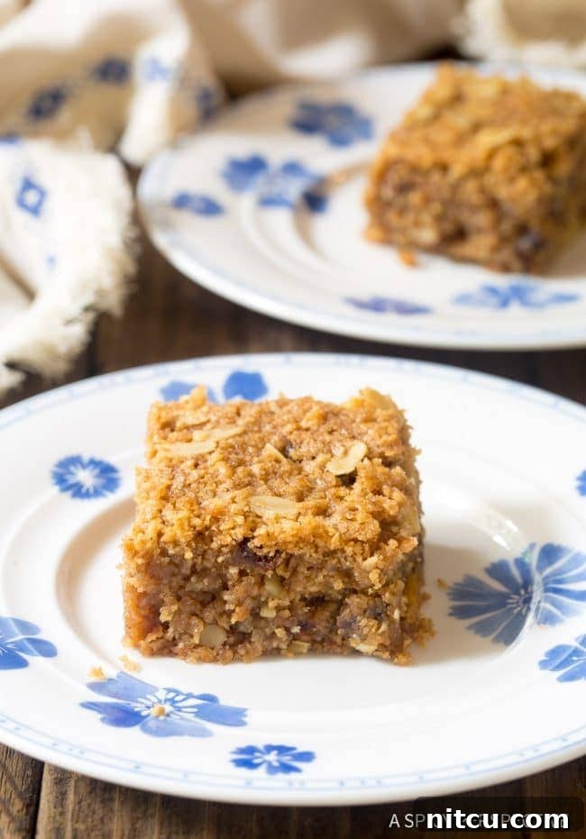 Wholesome Eggless Oat Bars 10 A single slice of egg-free breakfast oatmeal bar on a plate, showcasing visible nuts and dates.