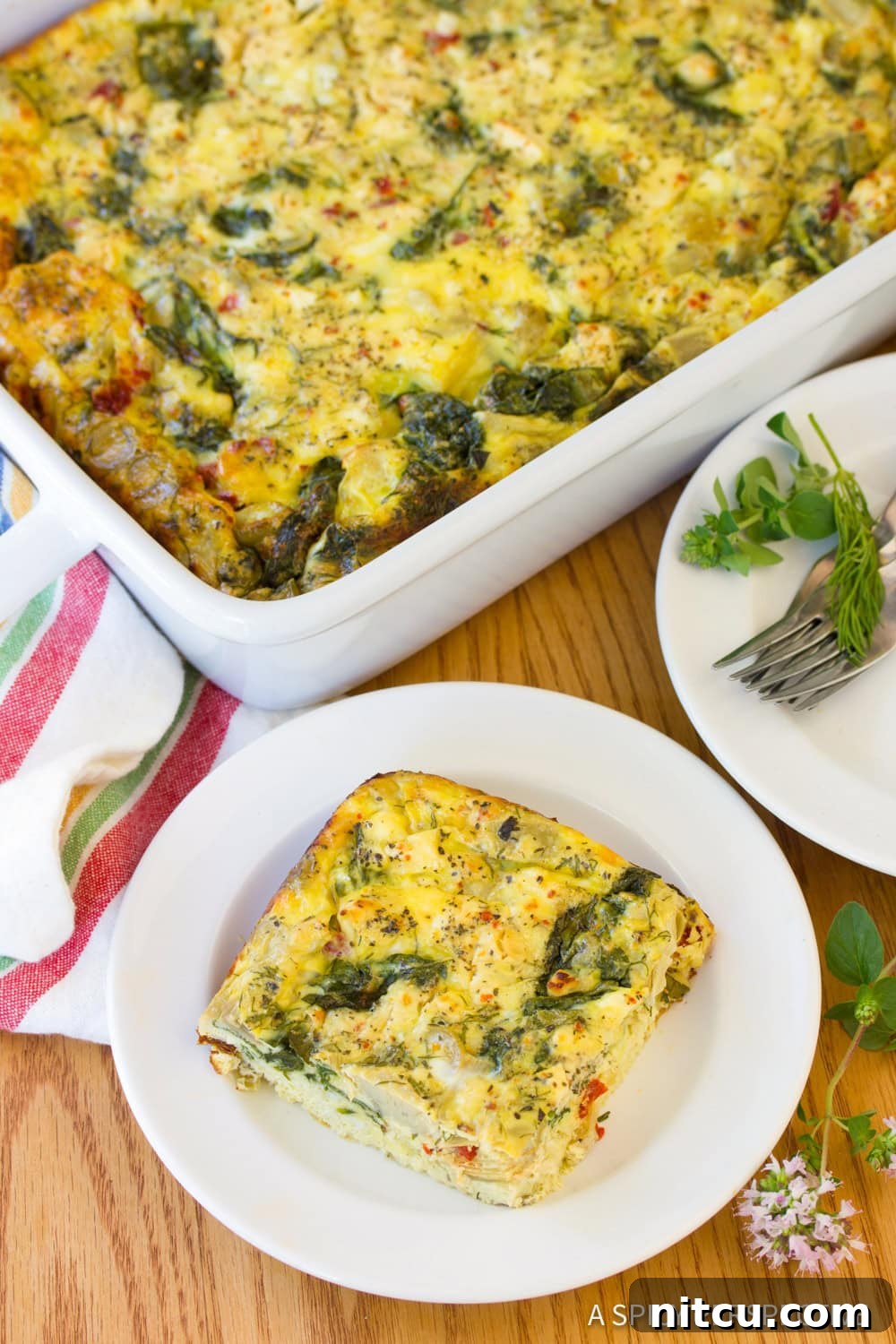 Savory Greek Omelette Bake 9 A perfectly portioned slice of Greek omelette casserole on a white plate, showcasing its fluffy texture and colorful ingredients.