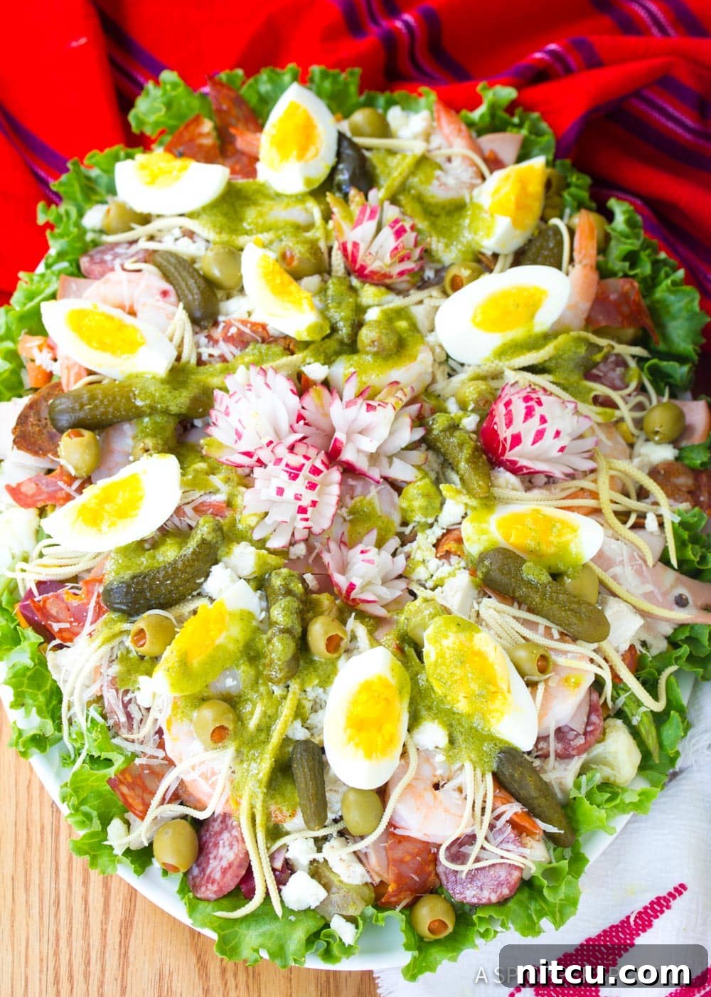 Layered Legacy: Guatemalan Fiambre 2 Large, colorful Fiambre salad on a serving platter with a vibrant red cloth underneath, showcasing its diverse ingredients.