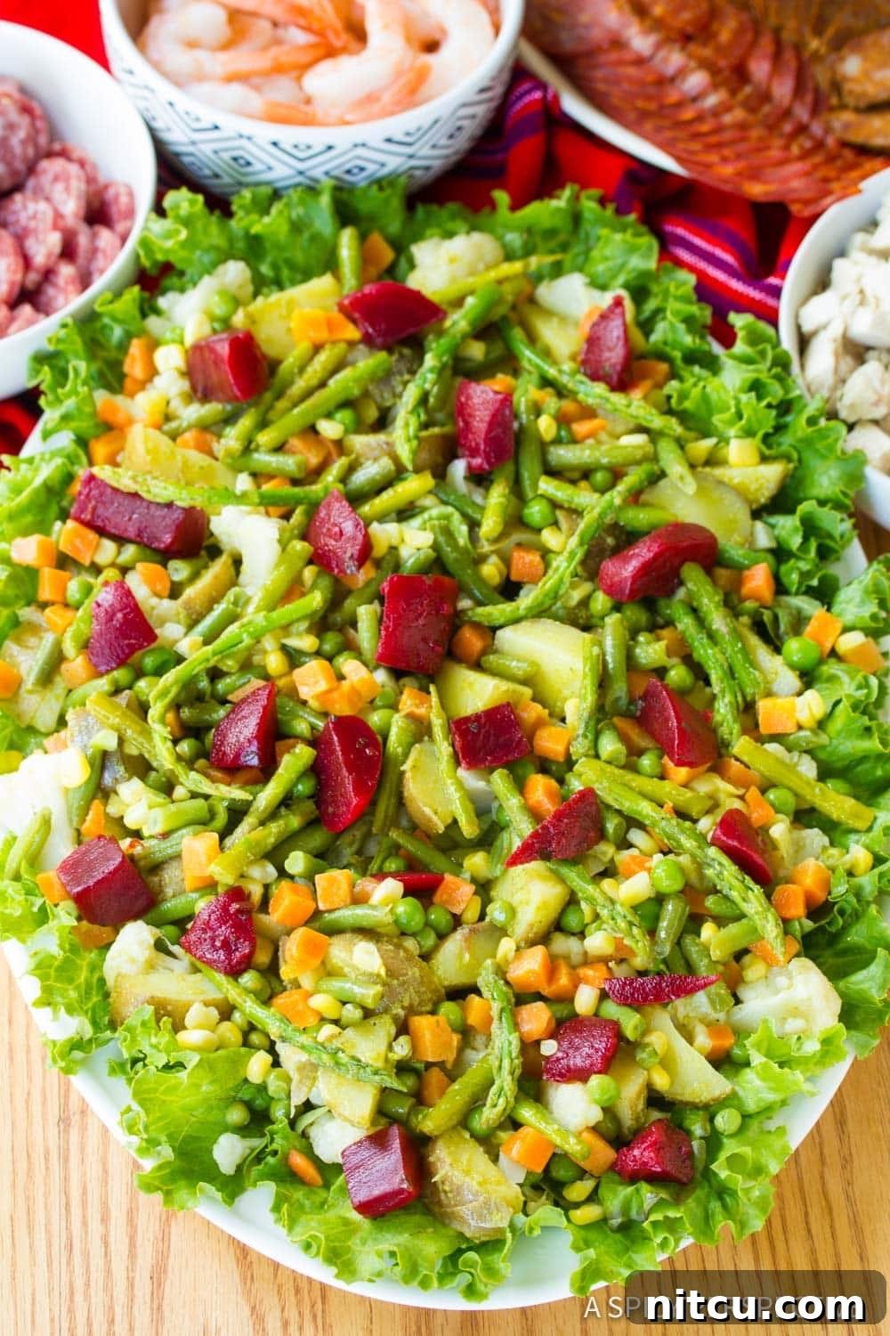 Layered Legacy: Guatemalan Fiambre 5 A large serving platter piled high with vibrant Guatemalan Fiambre salad, surrounded by various individual ingredients in bowls.
