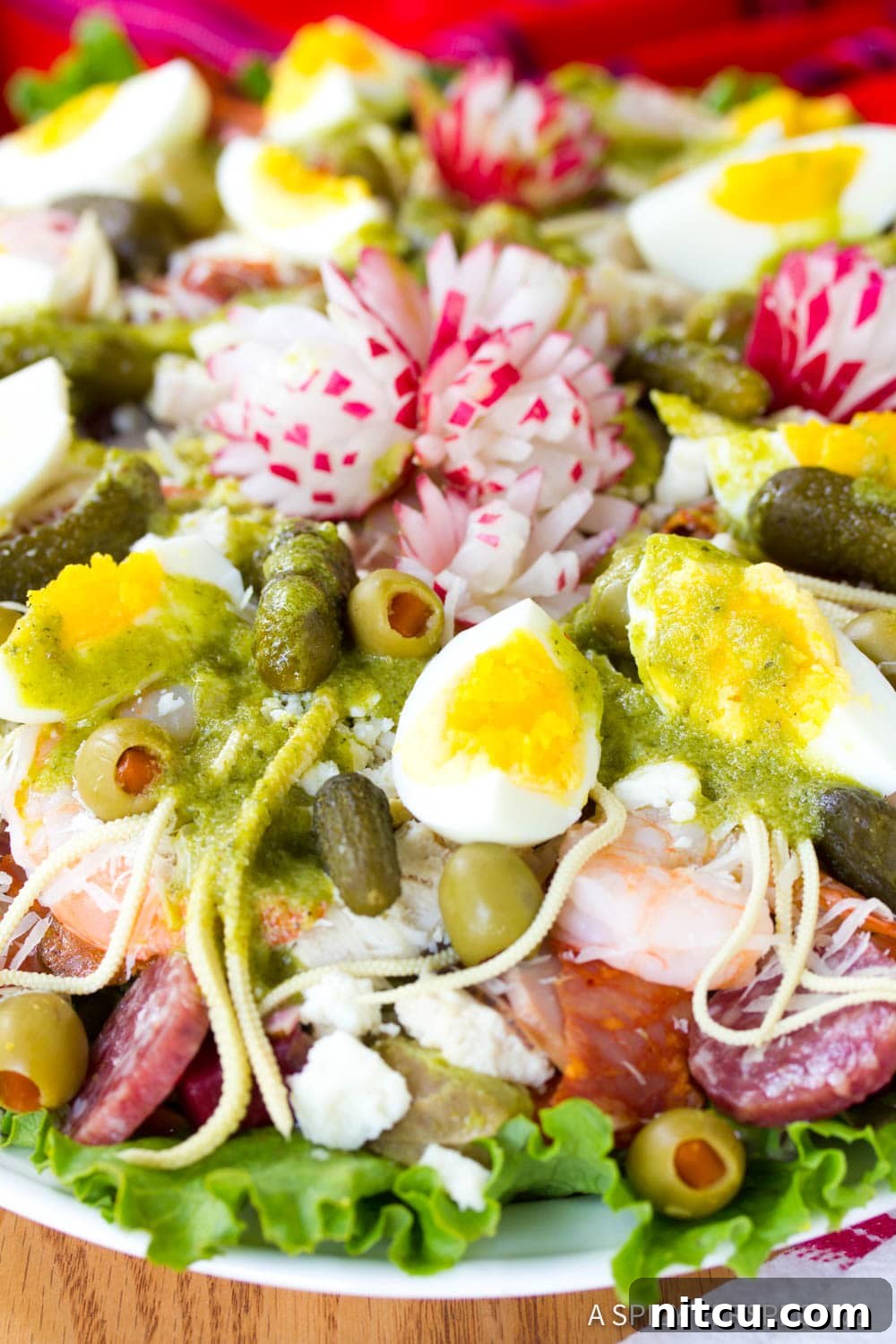 Layered Legacy: Guatemalan Fiambre 8 A close-up of Fiambre salad featuring lettuce, an assortment of cured meats, olives, pickles, hard-boiled eggs, and decorative radishes.