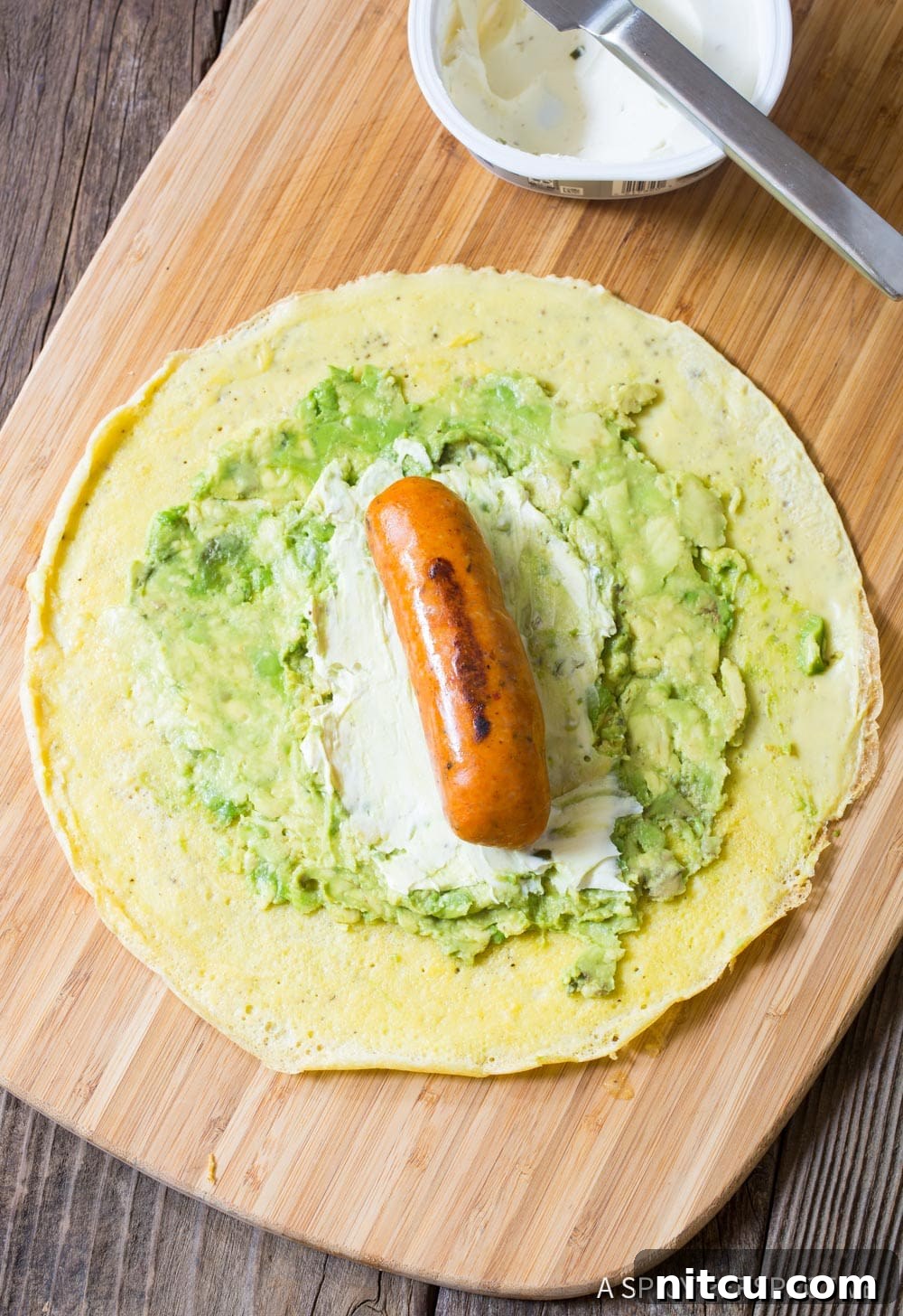 Quick Keto Egg Wraps 7 Assembling the keto breakfast egg wraps on a wooden cutting board.
