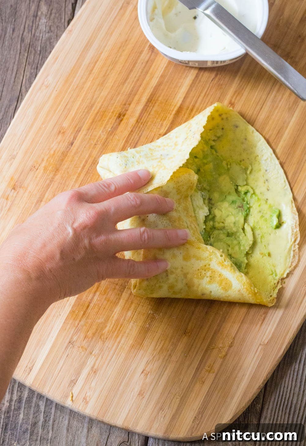 Quick Keto Egg Wraps 8 Hand wrapping a breakfast wrap up.