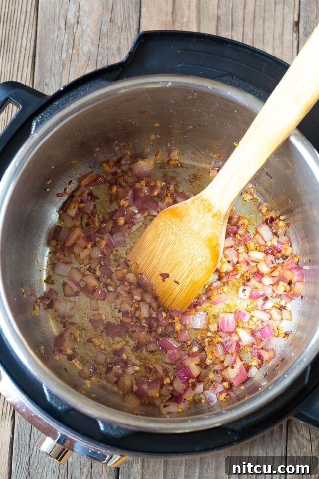 Velvety Instant Pot Vodka Shrimp Pasta 5 Onions and garlic sauteing in an instant pot.