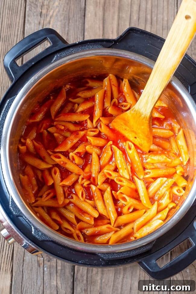 Velvety Instant Pot Vodka Shrimp Pasta 7 Penne pasta cooking in the tomato sauce in an instant pot.