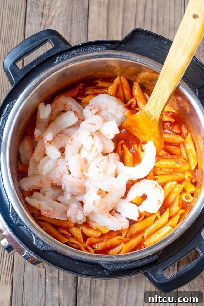 Velvety Instant Pot Vodka Shrimp Pasta 8 Shrimp being added to the pasta and sauce.