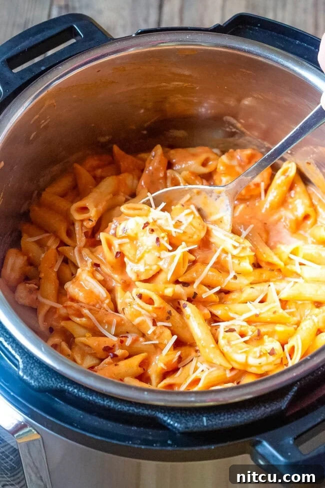 Velvety Instant Pot Vodka Shrimp Pasta 9 Shrimp pasta with vodka sauce in an instant pot with a spoon in the pot.