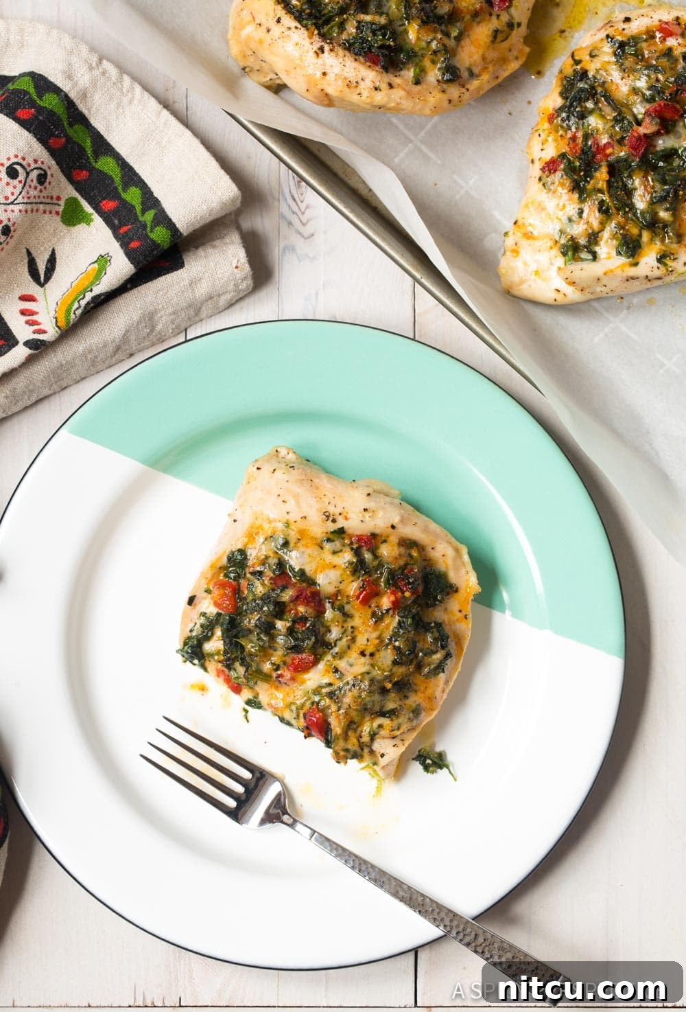 Creamy Spinach-Stuffed Chicken 4 Cheesy Spinach Stuffed Chicken Breast cut in half on a plate with a fork.