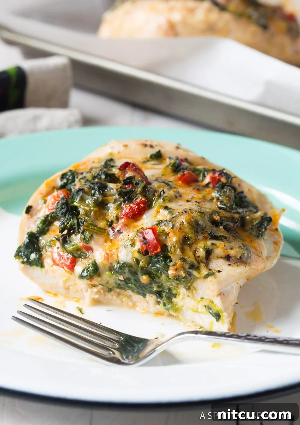 Creamy Spinach-Stuffed Chicken 7 Close up shot of chicken breast with toppings, cut in half on a plate.