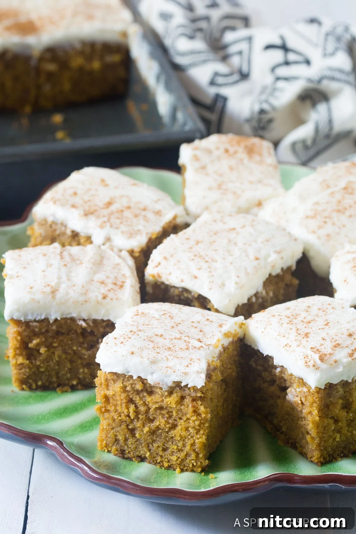 Harvest Pumpkin Slab Cake 10 Easy Pumpkin Cake with Buttermilk Frosting, with several cut pieces artfully arranged on a serving platter.