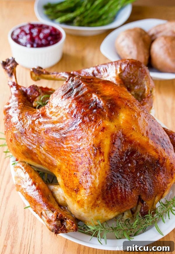 A perfectly roasted turkey, garnished with fresh herbs, resting on a serving platter.
