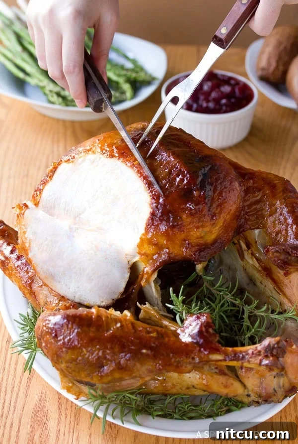 Hands expertly carving a whole roast turkey on a serving platter, revealing its juicy interior.