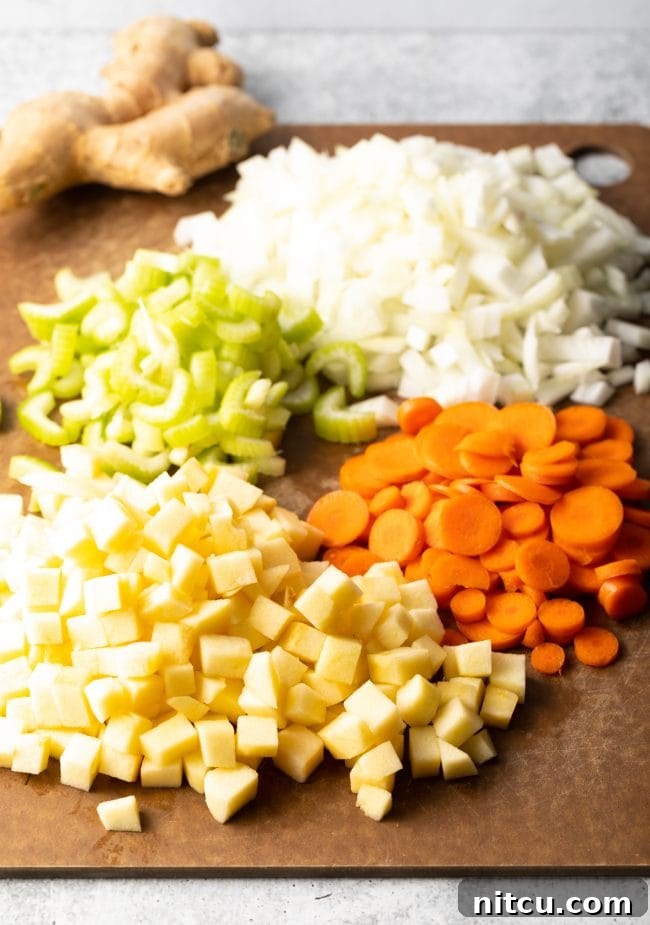 Nourishing Mulligatawny Delight 4 A cutting board laden with freshly chopped ingredients including onions, celery, carrots, and apples, ready for Mulligatawny soup preparation.