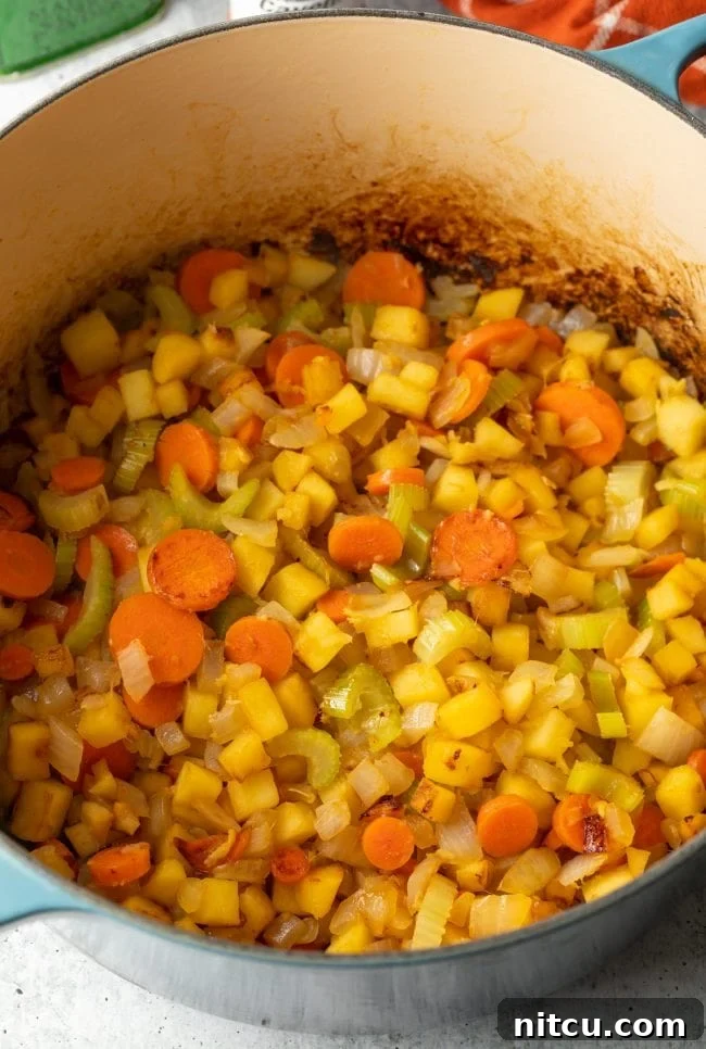 Nourishing Mulligatawny Delight 5 A close-up view of a pot on the stove, showing onions, vegetables, and apples browning and sautéing, releasing their aromatic flavors.
