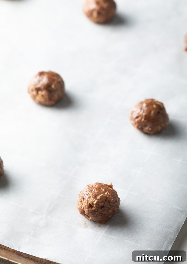 Chewy Oatmeal Cream Pie Bliss 3 Balls of oatmeal cookie dough perfectly portioned on parchment paper-lined baking sheets.