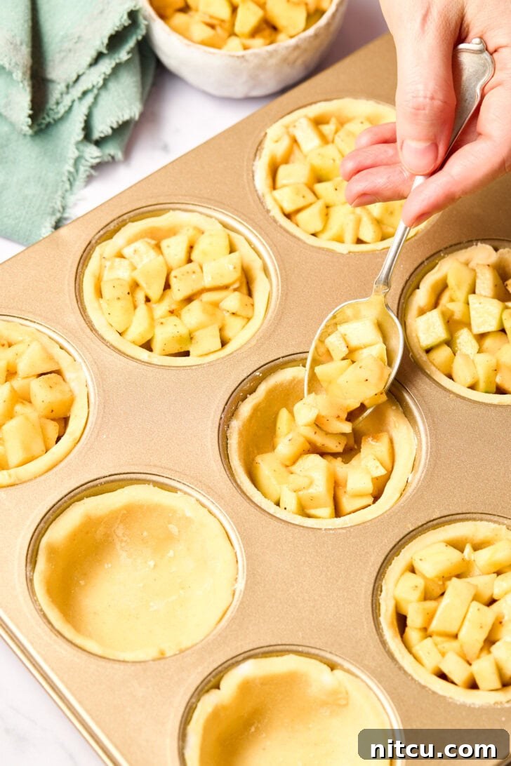 Individual Apple Tarts 6 Mini Apple Pie Recipe - filling the prepared cornmeal pie crusts in a muffin tin with the rich apple mixture.