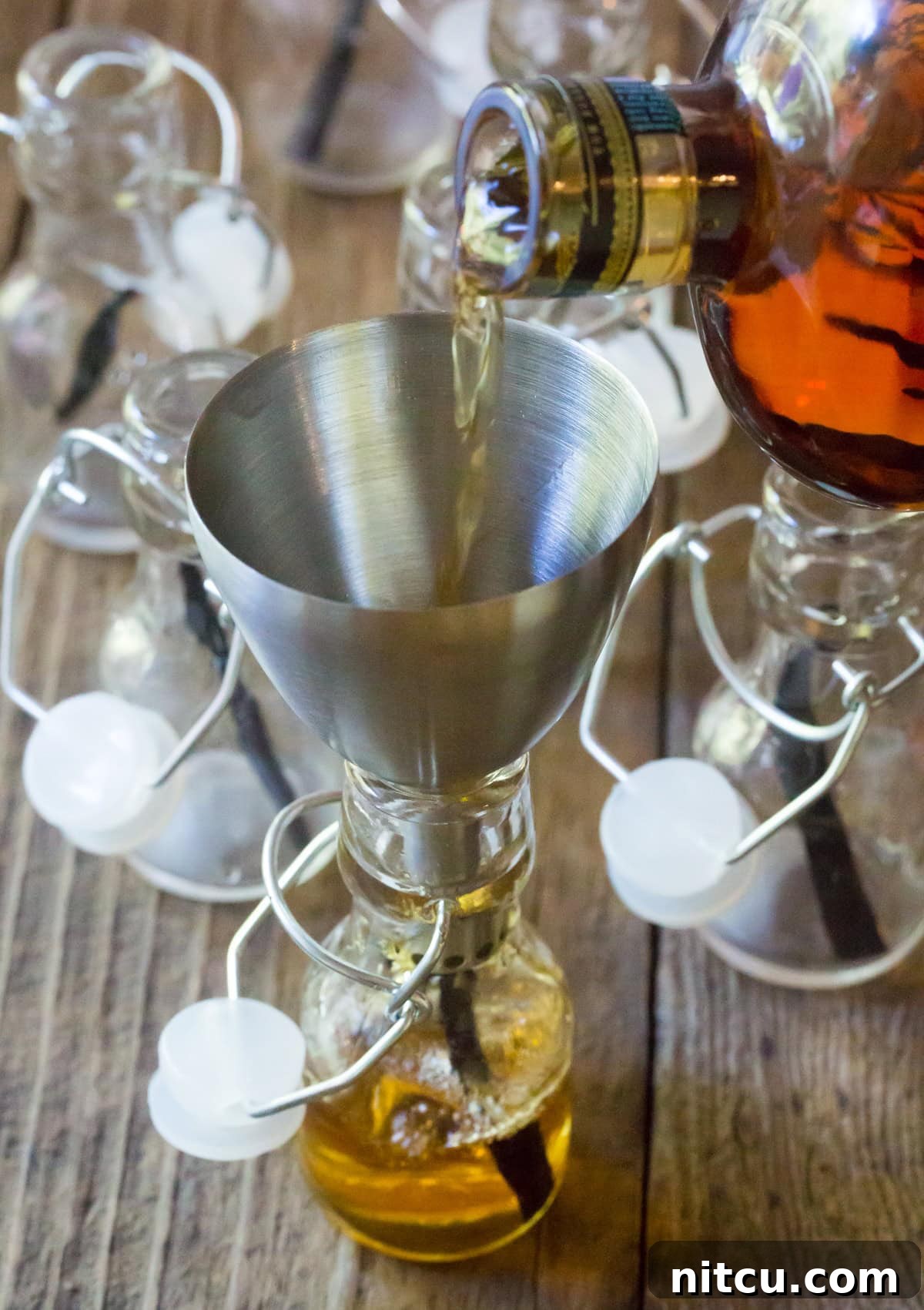 Artisan Bourbon Vanilla Extract 6 Pouring bourbon into the small bottles using a funnel.