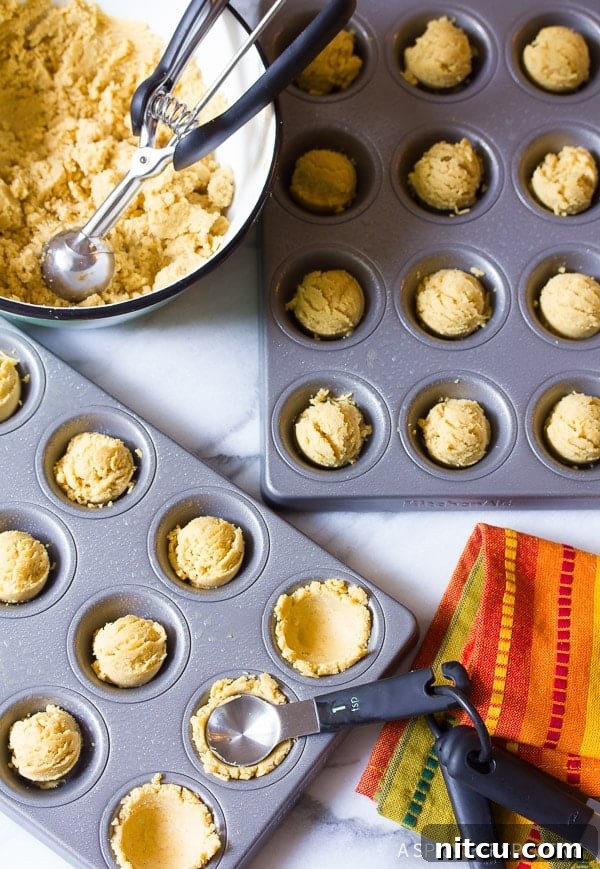 Bite-sized Tamales 7 Masa batter being carefully spooned into individual compartments of a mini muffin tin.