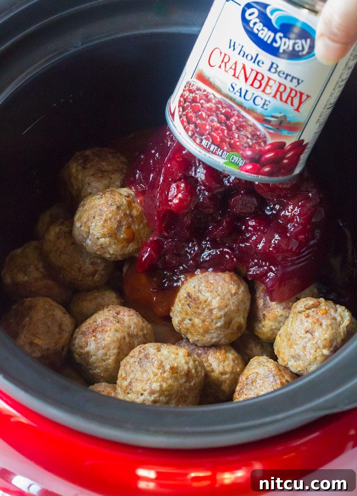 Crockpot Party Meatballs 7 Adding canned whole cranberry sauce over the main ingredients in the Crock-Pot
