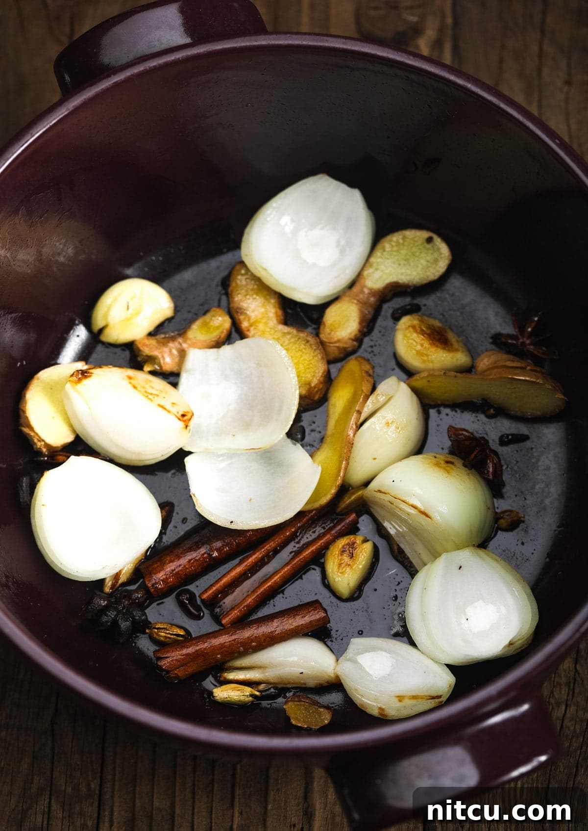 Wholesome Pho Creation 6 Onion, ginger, garlic, and whole spices sizzling in coconut oil at the bottom of a large pot, beginning to release their rich aromas.