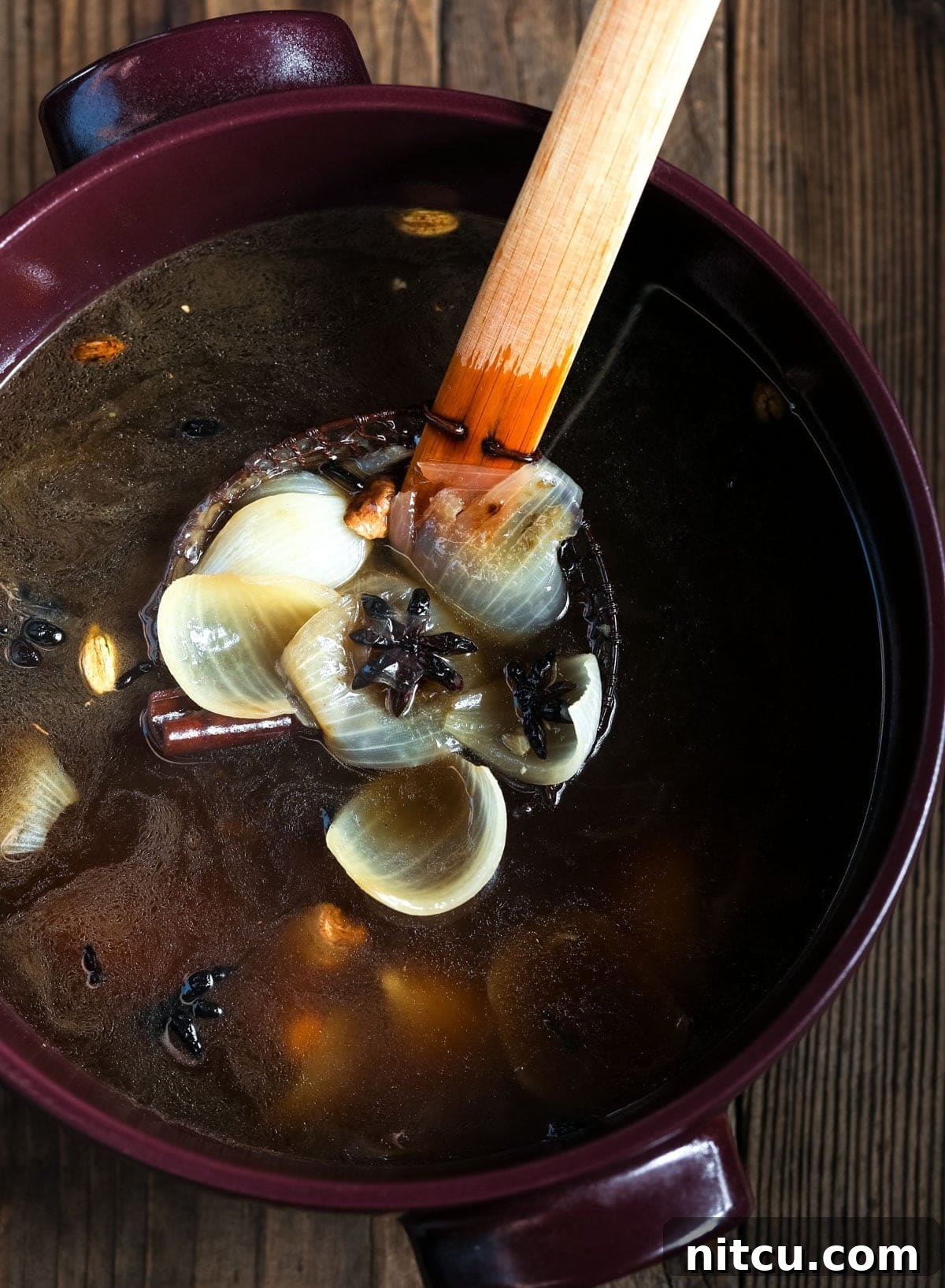 Wholesome Pho Creation 8 A ladle gently skimming aromatics from a large pot of rich Vietnamese broth, leaving a clear and flavorful base.