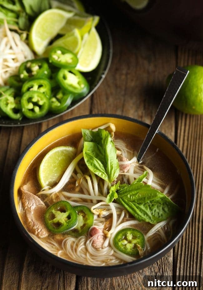 Wholesome Pho Creation 10 Adding a medley of fresh garnishes like basil, jalapeños, and lime to a steaming bowl of homemade pho soup for a burst of flavor.