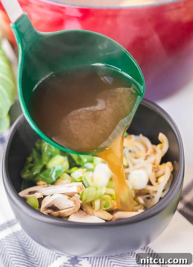 Hearty Chicken Hot Pot 10 Ladle pouring broth over veggies in a bowl.