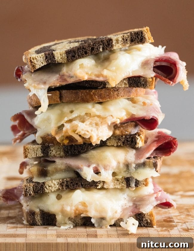 Golden Baked Reuben Sandwich 2 Reuben sandwiches stacked on top of each other, showcasing crispy bread and melted cheese.