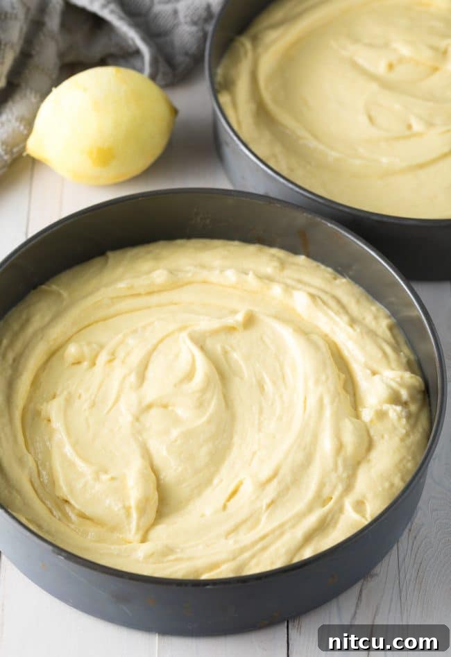 Smooth lemon buttermilk cake batter being poured into a greased and parchment-lined cake pan, ready for baking.