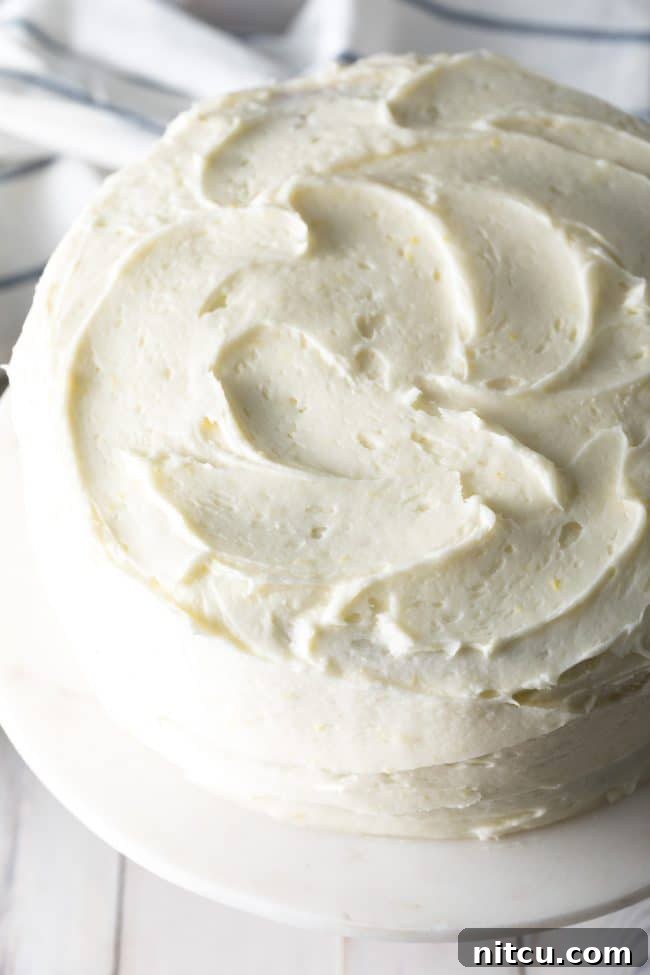 A grand, fully frosted Lemon Buttermilk Cake showcased on a cake stand, ready for its big reveal, embodying Southern hospitality.